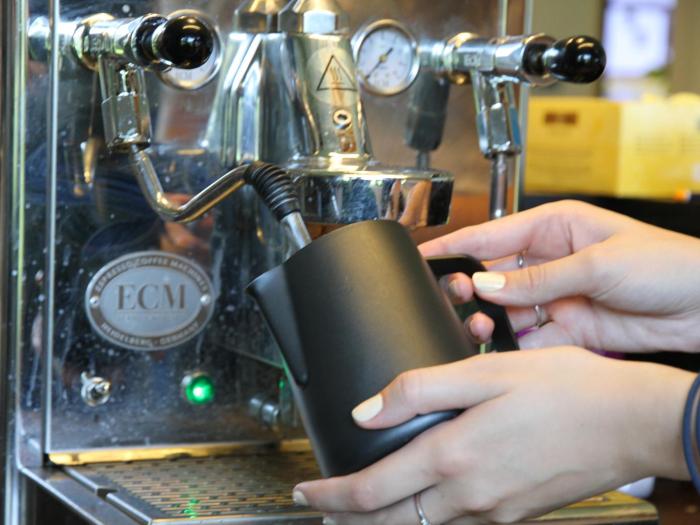 En studerende steamer mælk i caféen på vores kaffemaskine.
